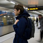 Young man with a backpack on standing on a subway platform.